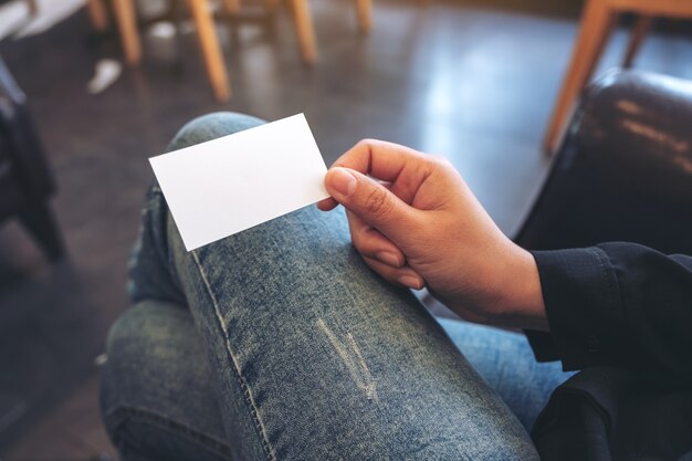 Una mujer sosteniendo una tarjeta blanca vacía mientras está sentado en la oficina