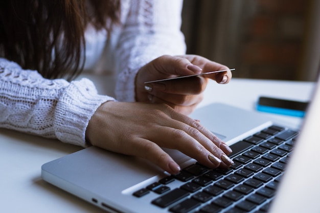 Foto mujer sosteniendo tarjeta de crédito en la computadora portátil para el concepto de compras en línea