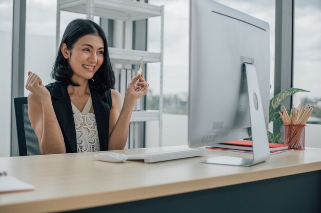 Mujer sosteniendo una tarjeta de crédito y usando una computadora de escritorio