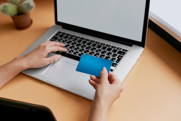 Mujer sosteniendo una tarjeta de crédito y usando una computadora portátil Concepto de compras en línea