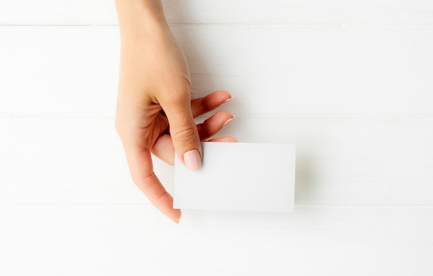 Mujer sosteniendo una tarjeta de presentación blanca en la mano para su diseño