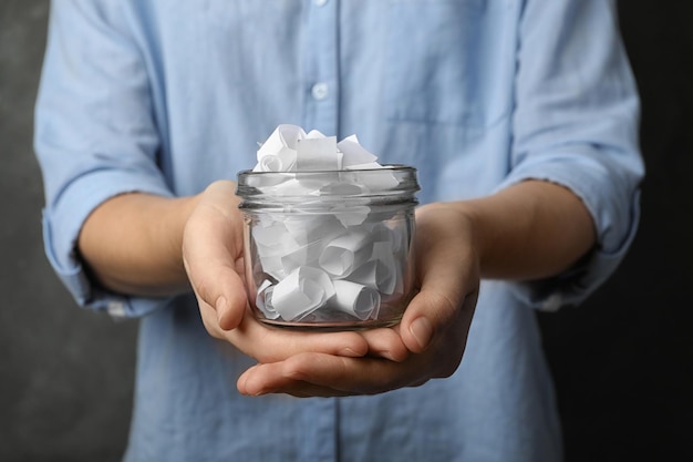 Mujer sosteniendo un tarro de cristal con piezas de papel en las manos