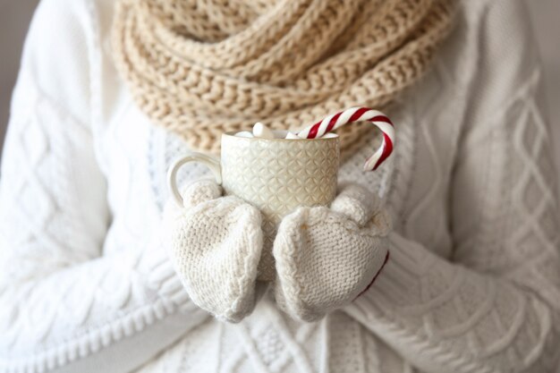 Mujer sosteniendo la taza con bastón de caramelo de Navidad en las manos