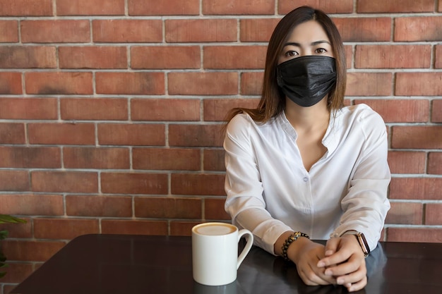 Foto mujer sosteniendo una taza de café contra la pared