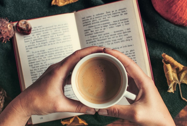 Foto mujer sosteniendo una taza de café sobre un libro