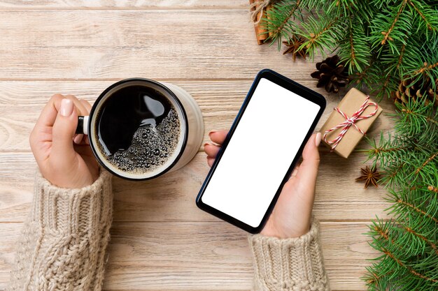 Mujer sosteniendo la taza de café y teléfono inteligente