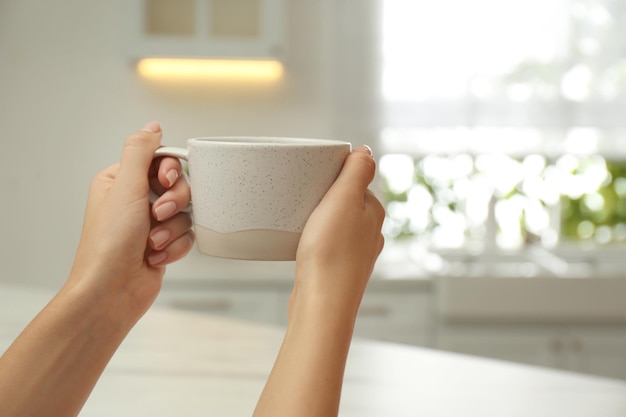 Mujer sosteniendo una taza elegante en primer plano de la cocina