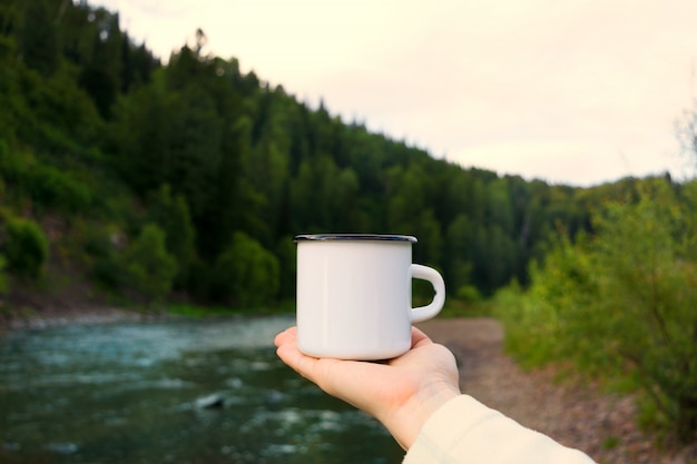 Mujer sosteniendo taza de esmalte con vista al río