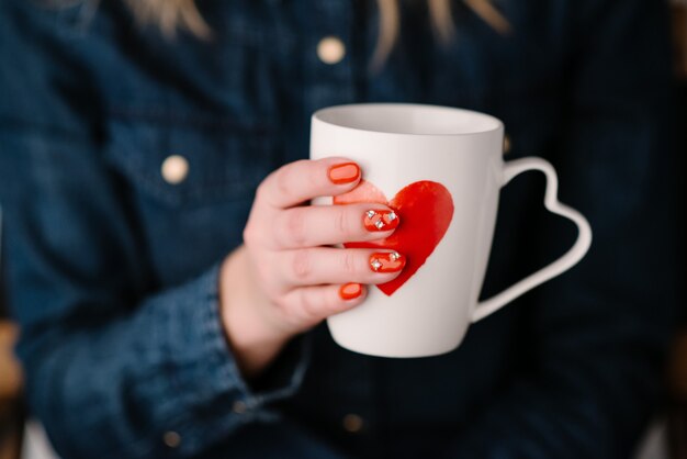 Mujer sosteniendo la taza con forma de corazón. De cerca