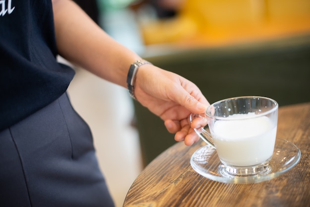 Mujer sosteniendo una taza de leche caliente sobre la mesa