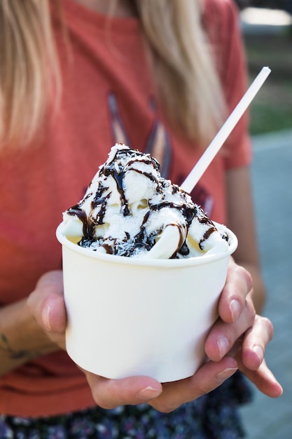 Mujer sosteniendo una taza para llevar con helado o yogur helado