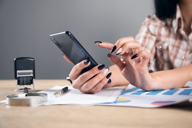 Mujer sosteniendo teléfono y informe gráfico de trabajo