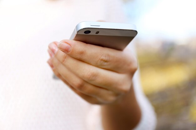 Mujer sosteniendo teléfono inteligente afuera