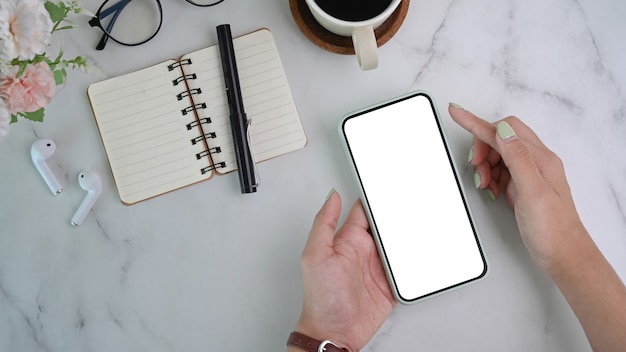 Mujer sosteniendo un teléfono inteligente en el escritorio