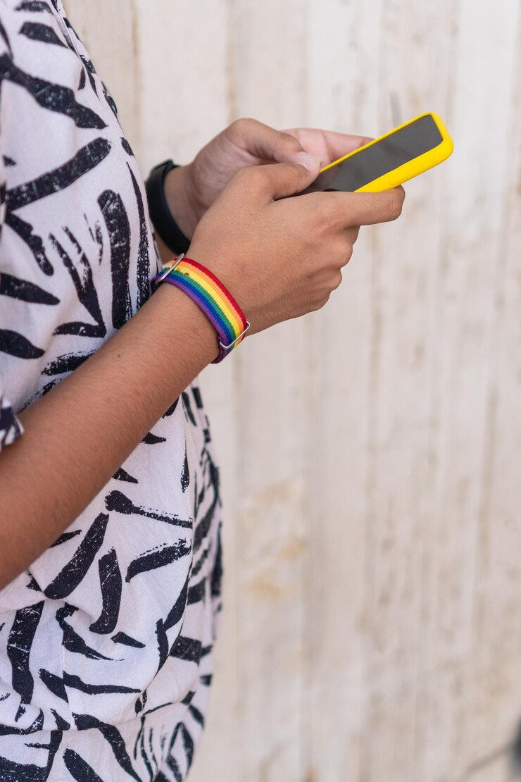 Foto mujer sosteniendo un teléfono inteligente y mirándolo mientras está de pie en la calle
