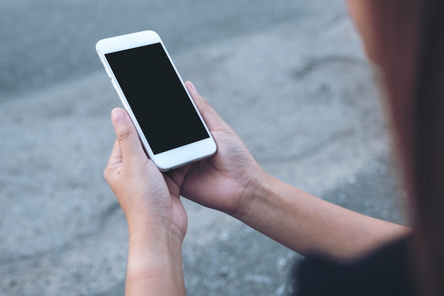 Mujer sosteniendo teléfono móvil blanco con pantalla negra en blanco