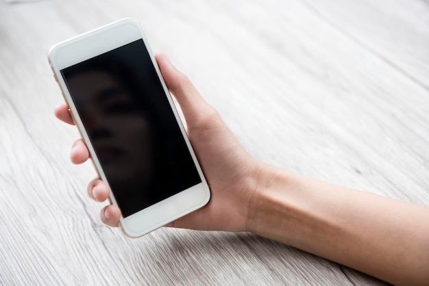 Mujer sosteniendo un teléfono móvil en la cafetería. Pantalla vacía para espacio de copia