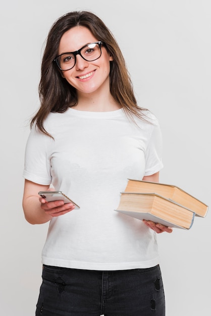 Mujer sosteniendo teléfono móvil y libros