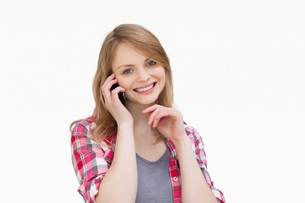 Mujer sosteniendo un teléfono móvil mientras mira a la cámara