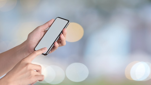 Foto mujer sosteniendo teléfono móvil y mostrando pantalla en blanco para montaje gráfico