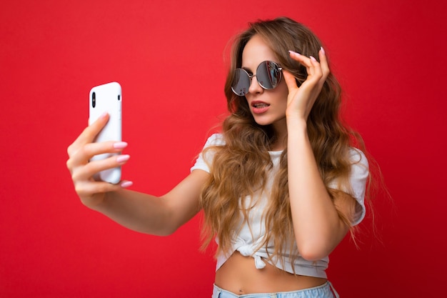 Mujer sosteniendo teléfono móvil tomando fotos selfie con cámara de teléfono inteligente