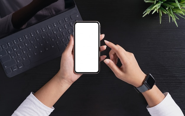 Foto una mujer sosteniendo el teléfono que muestra la pantalla en blanco en la vista superior