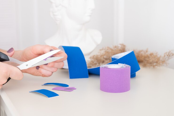 Foto mujer sosteniendo tijeras, cortando cinta de kinesio. tratamiento antiedad contra las arrugas. concepto de encintado estético.