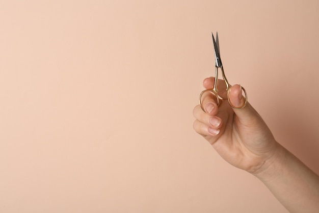 Mujer sosteniendo tijeras de coser sobre fondo beige primer plano Espacio para texto
