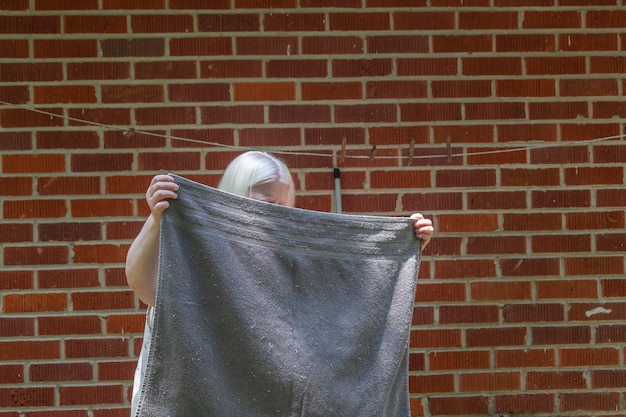 Foto mujer sosteniendo una toalla contra una pared de ladrillo