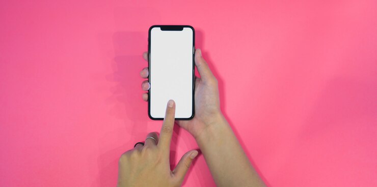 Foto mujer sosteniendo y tocando la pantalla en blanco smartphone en rosa