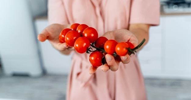 Mujer sosteniendo tomates cherry maduros en las manos