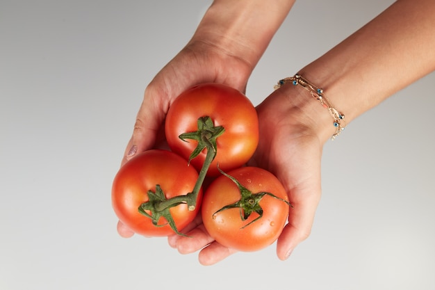 Mujer sosteniendo tomates sobre fondo blanco.