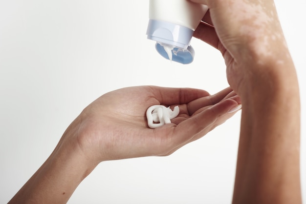 Mujer sosteniendo el tubo de crema y aplicando crema humectante en sus hermosas manos.