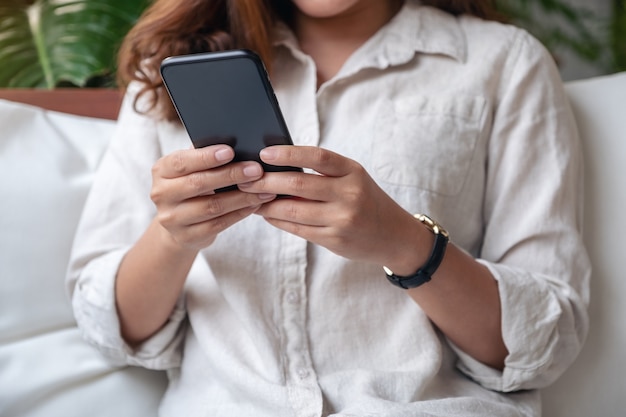 Mujer sosteniendo, usando y mirando el teléfono inteligente en el café