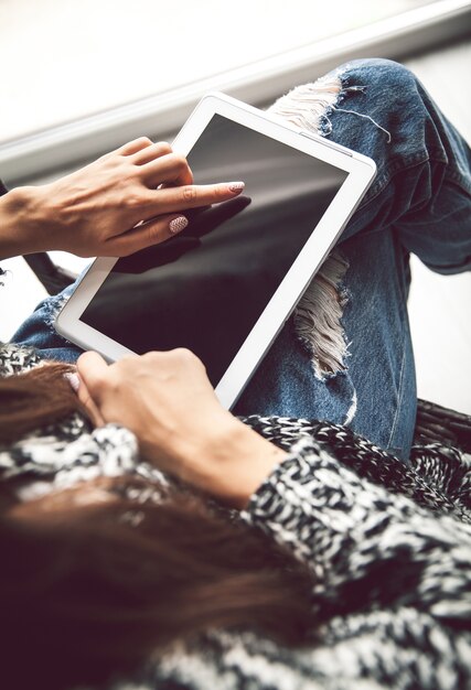 Mujer sosteniendo y usando tableta con pantalla vacía.