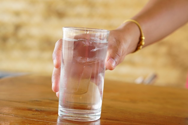 mujer sosteniendo un vaso de agua sobre la mesa