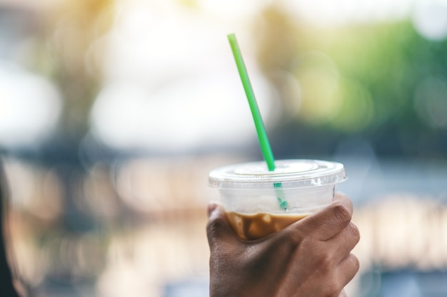 Una mujer sosteniendo un vaso de plástico de café helado con paja