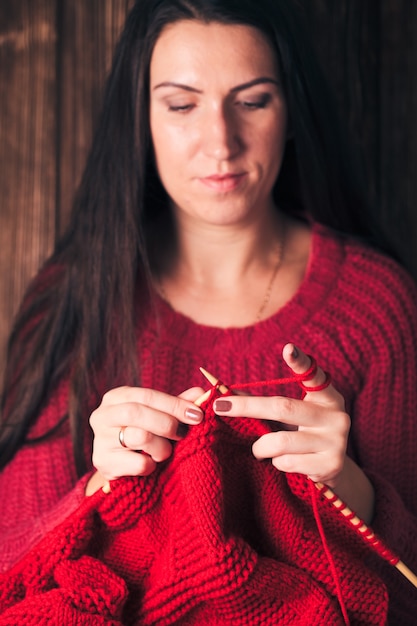 Mujer sostiene agujas y tejer una chaqueta roja