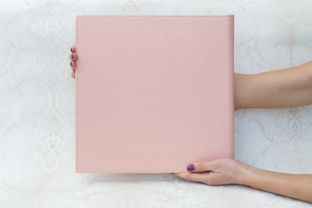 Una mujer sostiene un álbum de fotos familiar. la persona mira el libro de fotos. muestra de álbum de fotos rosa. Álbum de fotos de boda con cubierta de cuero.