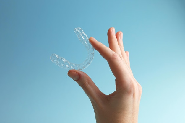 Foto una mujer sostiene un aparato ortopédico de plástico transparente en la mano.