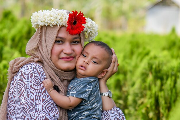 Foto una mujer sostiene a un bebé con una corona de flores.