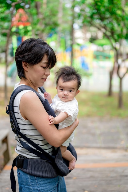 Una mujer sostiene a un bebé en un portabebés.