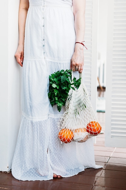 Mujer sostiene una bolsa con alimentos verduras y frutas frescas