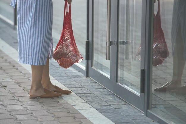 La mujer sostiene una bolsa de malla con productos.