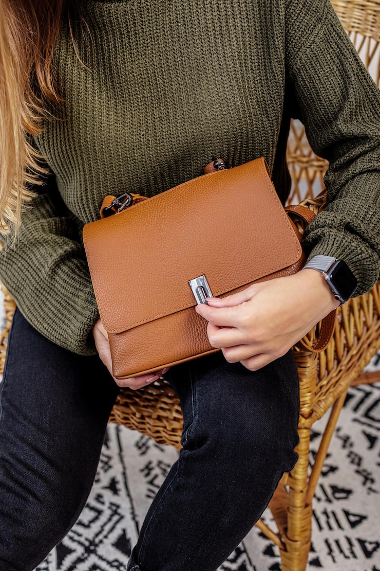 Foto una mujer sostiene un bolso de moda de cuero marrón en sus manos. nueva colección de bolsos de mujer