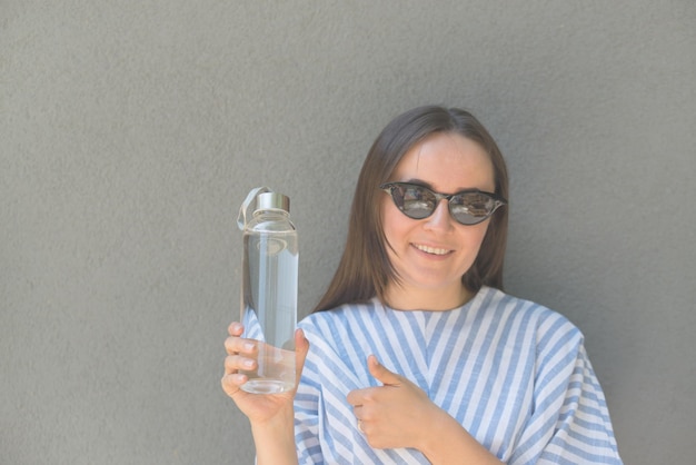 La mujer sostiene una botella de vidrio con agua clara