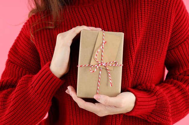 Mujer sostiene caja de regalo sobre fondo rosa, cerrar