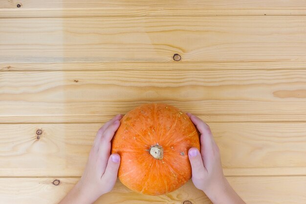 La mujer sostiene una calabaza. Manos femeninas con manicura de mármol de otoño de moda en color naranja