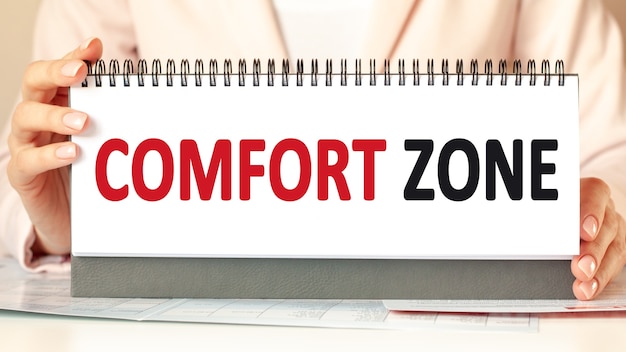 mujer sostiene un cartón con las manos con el texto COMFORT ZONE.