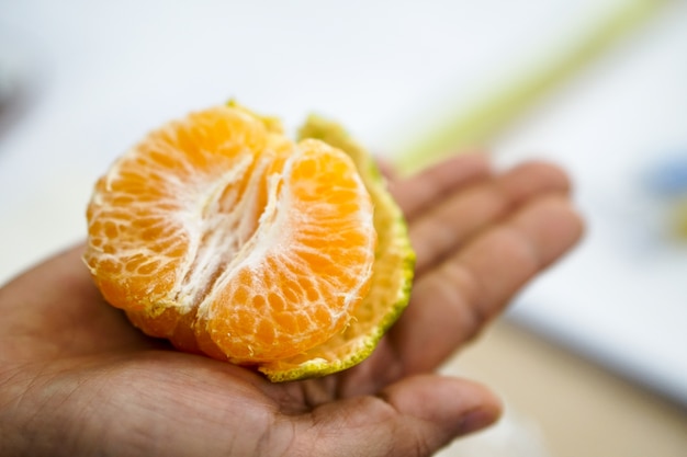 La mujer sostiene la cáscara de naranja.